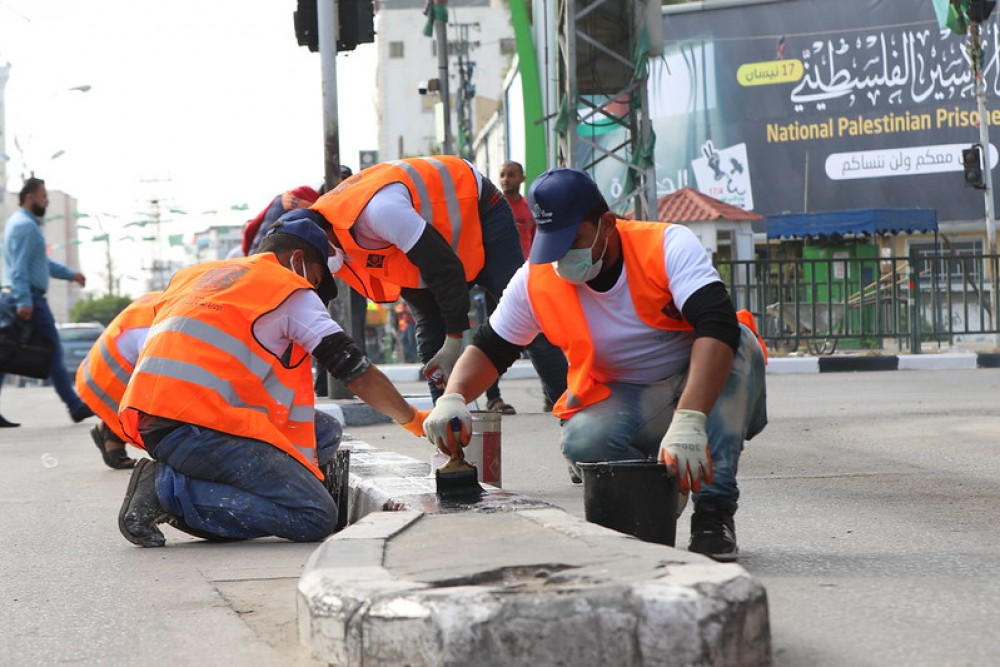 طواقم بلدية غزة يدهنون أحجار الجبهة في الشوارع الرئيسة للمدينة