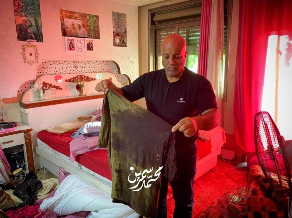 والد الشهيد يحمل ملابس ابنه التي كان يرتديها عند اصابته