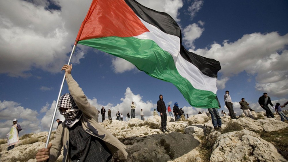 شاب يحمل العلم الفلسطيني على الحدود الشرقية لقطاع غزة