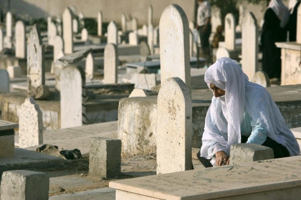 امرأة تجلس بجوار قبر