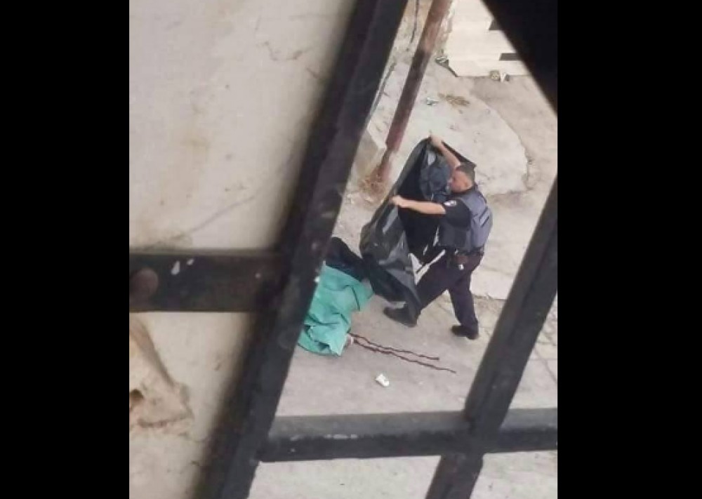 جندي بجيش الاحتلال يقوم بوضع غطاء على الشهيد