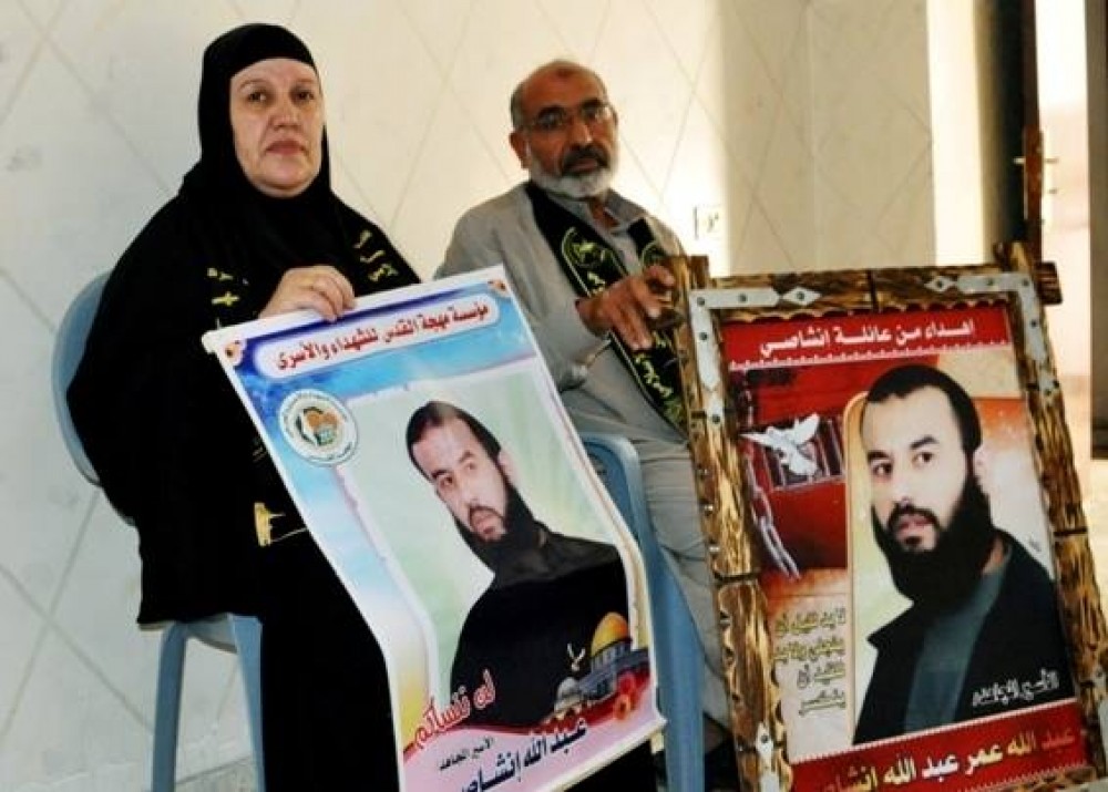 والدا الأسير انشاطي يحملان صور ابنهم